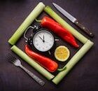 an image of chilis and clock in the center of fork and knife
